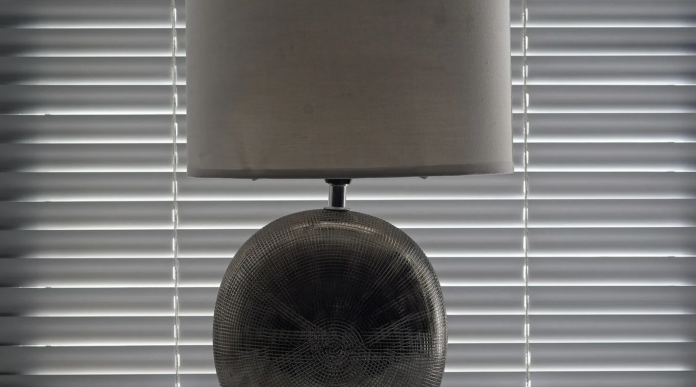 Graue Tischlampe vor einer hellen Jalousie